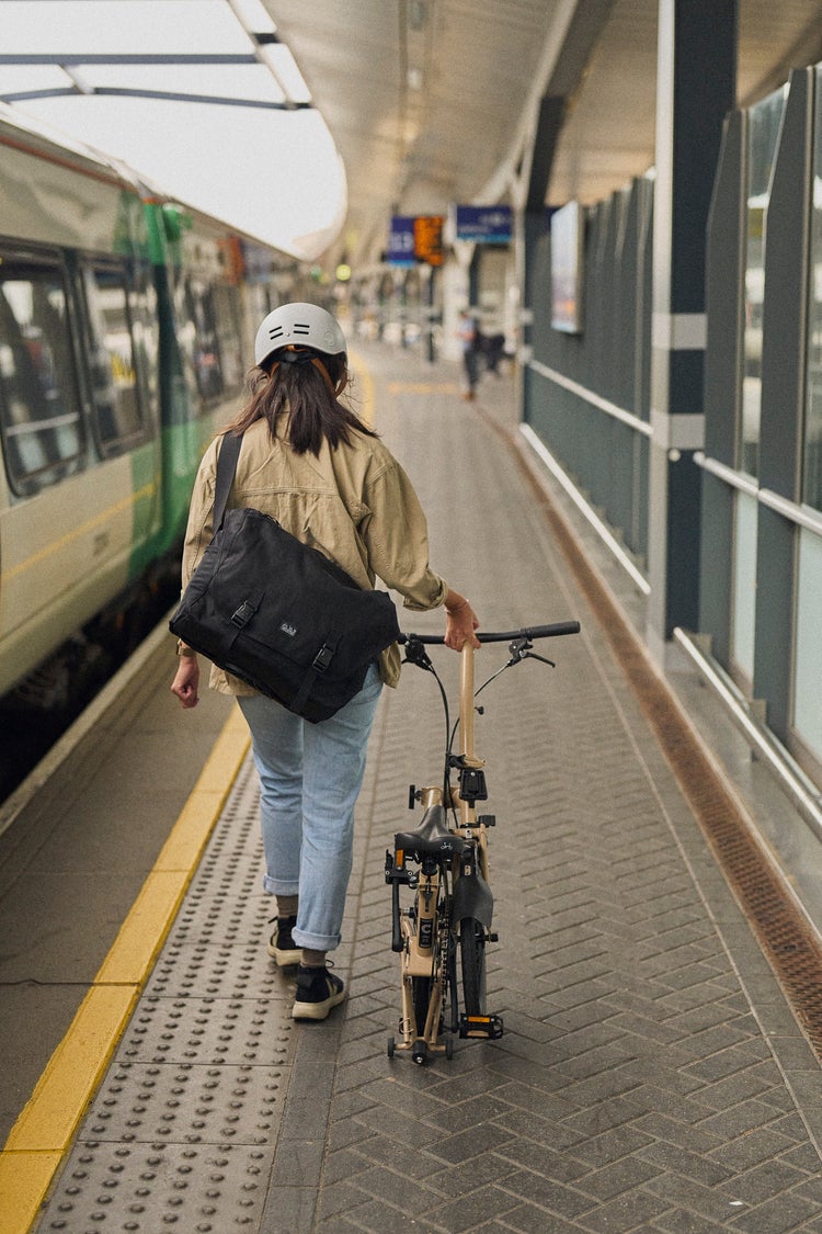 A person carrying a folded Brompton C Line up a flight of stairs