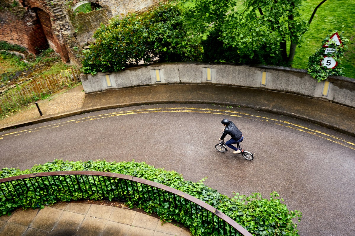 man riding brompton c line outside building