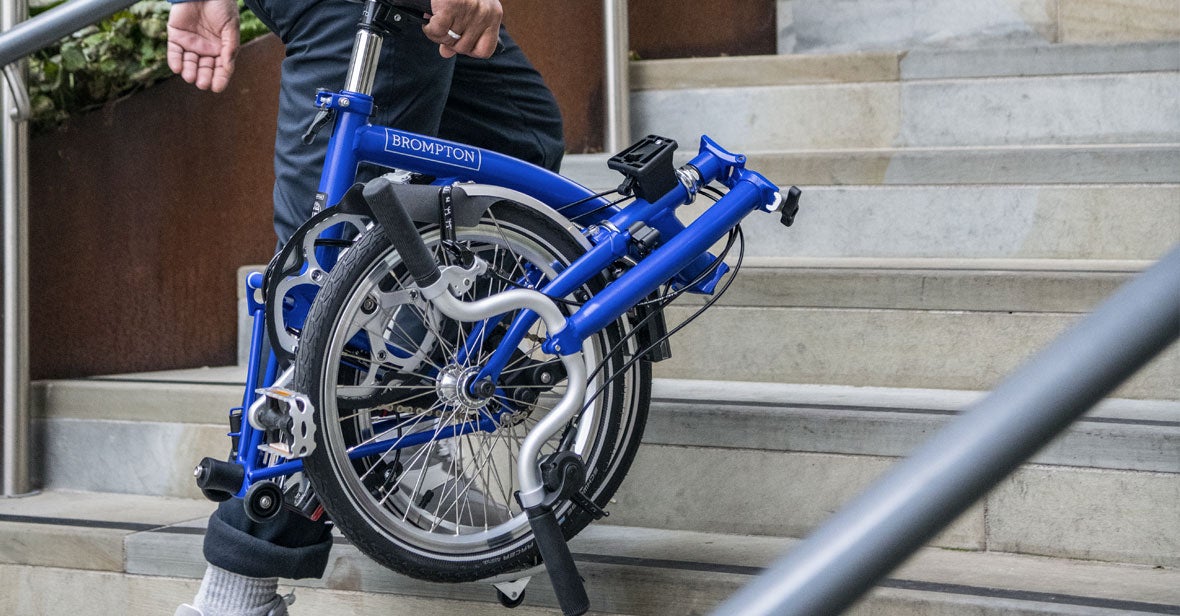 Folded brompton bike being carried up stairs