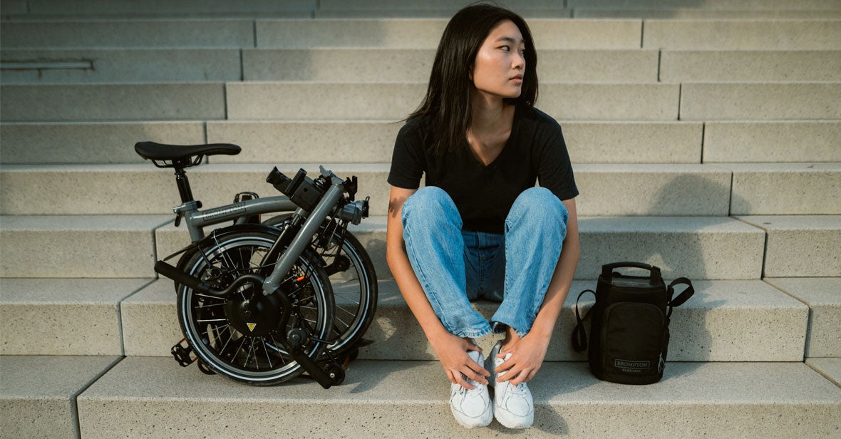Woman sat on step with folded electric Brompton