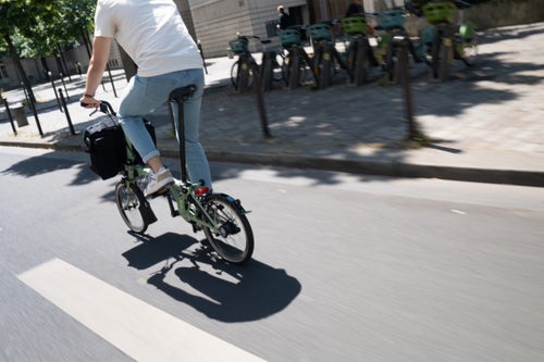 person riding brompton c line in matcha green through city