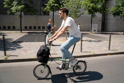 man riding brompton c line in matcha green with luggage on road