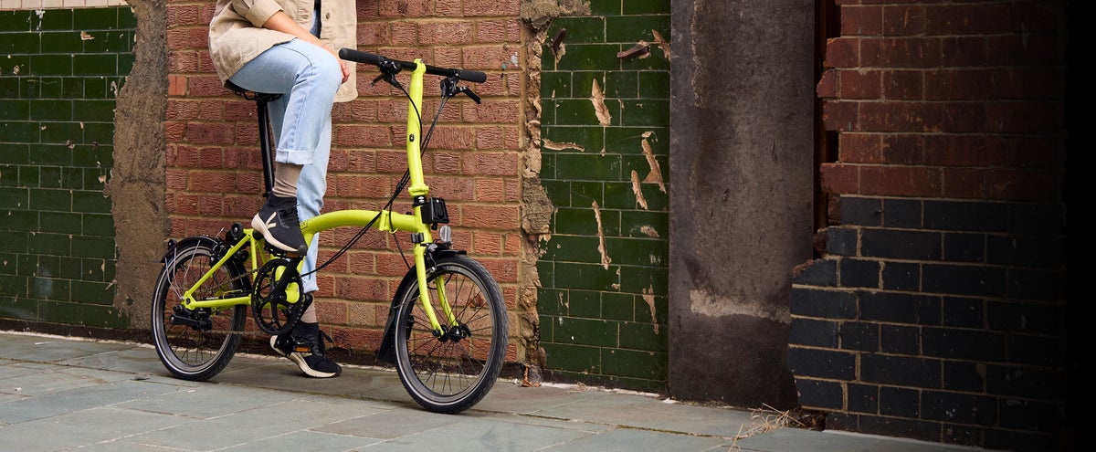 A person carrying a folded Brompton C Line up a flight of stairs